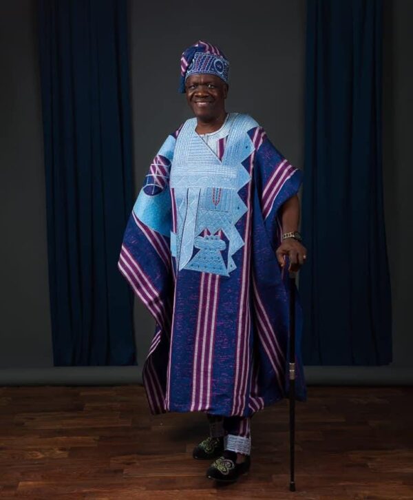 Aso oke Agbada with a mix of blue and purple with intricate light blue embroidery paired with a matching cap and styled with classic accessories
